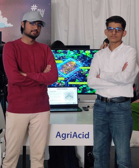 Three individuals in white shirts with arms crossed stand behind a table displaying a robot labeled "REEFSCAPE" and electronic equipment. Three individuals in red jackets with arms crossed stand behind a table displaying a robot labeled "AL-KHWARIZMI-4" and electronic devices. Two individuals in red shirts with arms crossed stand behind a table displaying a robot and a water basin. Two individuals in casual clothing with arms crossed stand behind a table displaying a screen showing "AgriAcid" and electronic equipment. The background features banners with text and colorful designs.