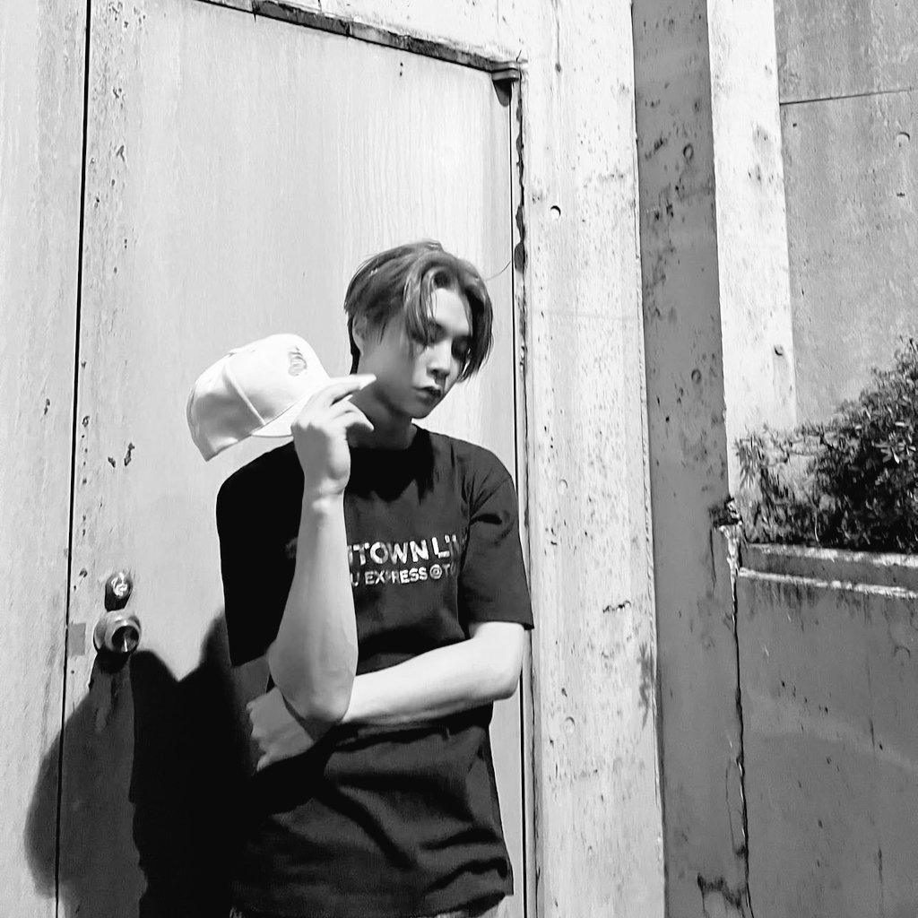 Standing coolly against a weathered wall, I strike a pose with my cap in hand, rocking a black tee and jeans. The urban vibe, soft lighting, and gritty backdrop capture my laid-back yet confident style on this afternoon, adding a touch of effortless charm to the scene.