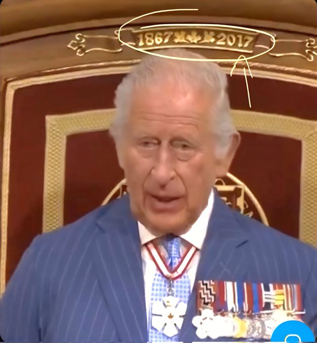 Charles III seated on an ornate throne with red and gold detailing. He wears a blue pinstripe suit, a red tie, a checkered sash, and medals on his chest. Above his head, the text "1867 * 2017" is visible on the throne\'s backrest.