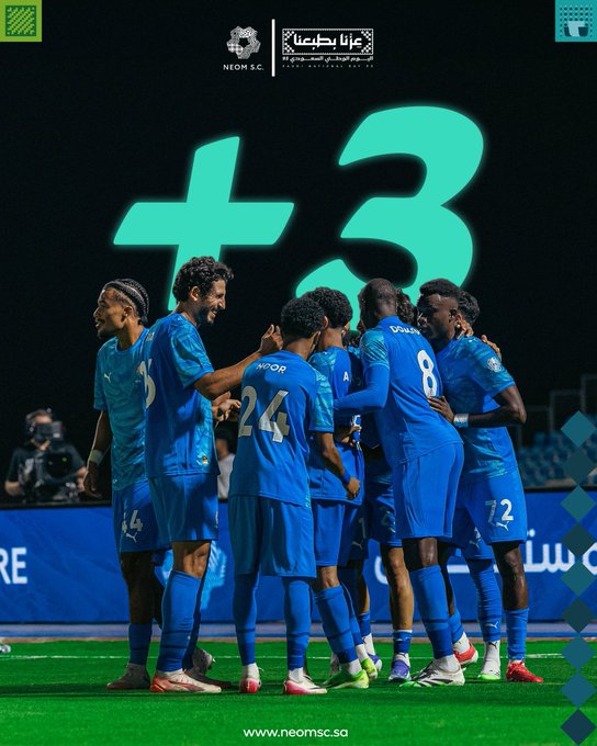 A group of soccer players in blue uniforms with numbers 8, 24, and 72 visible on their jerseys, standing together on a grassy field, celebrating with arms around each other. A large green number 3 and a plus sign are displayed in the background. Text overlays include Arabic and English phrases.
