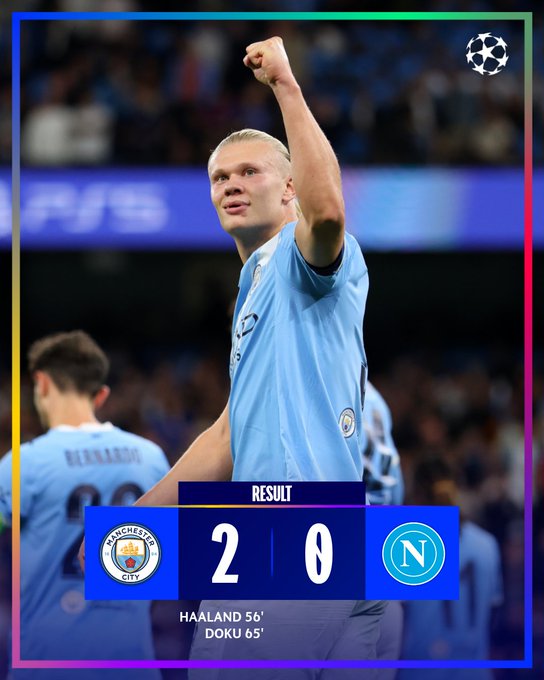 Erling Haaland wearing a light blue Manchester City jersey, raising his right fist in celebration on a soccer field. Another player in a similar jersey, Bernardo Silva, is visible in the background. The image includes text overlays showing "Manchester City 2 Napoli 0" and "Haaland 5\', Doku 85\'".