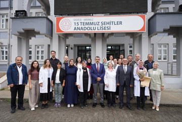 A man in a blue suit and red tie walking down a school hallway, shaking hands with a woman in a white coat. Students in casual clothing, some wearing jackets, walk alongside. A group of people, including individuals in white coats and suits, sit around a table in a room with lockers. A group of people, including men in suits and women in white coats, stand in front of a building with a sign reading "15 Temmuz Şehitler Anadolu Lisesi."