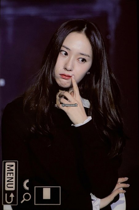 Jung Soojung with long dark hair, wearing a black outfit and white collared shirt. She has a thoughtful expression, touching her chin with one hand. A watermark with "@xxvxxl" is visible.