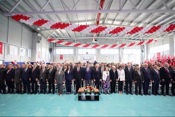 A group of people in formal attire standing together, cutting a ribbon at a school opening ceremony. Turkish flags and red-and-white balloons decorate the indoor space. A large banner displays "Esin Olcay Anadolu Lisesi Açılış Töreni" and images of individuals. Another image shows people, including children holding Turkish flags, walking outdoors with red flags in the background. A third image depicts a group of people posing on stairs inside a modern building with Turkish flags visible.