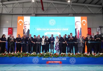 A group of people in formal attire standing together, cutting a ribbon at a school opening ceremony. Turkish flags and red-and-white balloons decorate the indoor space. A large banner displays "Esin Olcay Anadolu Lisesi Açılış Töreni" and images of individuals. Another image shows people, including children holding Turkish flags, walking outdoors with red flags in the background. A third image depicts a group of people posing on stairs inside a modern building with Turkish flags visible.