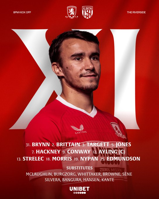 A man wearing a red Middlesbrough FC soccer jersey with white accents. The jersey has the club crest and sponsor logos. Large white Roman numeral "XI" is visible behind him. Text lists names including Brynn, Brittain, Jones, Hackney, Conway, Ayling, Strelec, Morris, Nypan, Edminson, and substitutes McLaughlin, Burgzorg, Whittaker, Browne, Sene, Silvera, Bangura, Hansen, Kante.