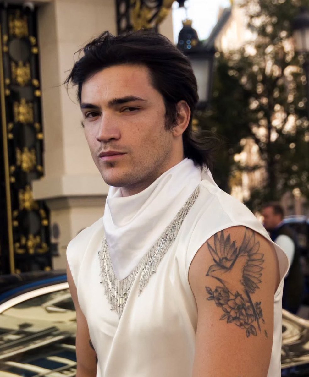 His silk top (or what looks like it) is the perfect fit for a soft boy. Bonus point, the fact that there are no sleeves so it lets the tattoos out. That bird about to fly, on its flower branch, adds to the softness of it all 💓