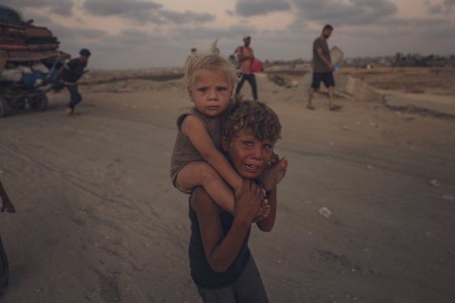 🔴 #GAZA ESCENA INSOPORTABLE: Cansado y llorando, un niño carga a su hermana pequeña en su espalda, obligado a caminar largas distancias durante un nuevo desplazamiento forzado por parte del ejército israelí, que dio un plazo de 48 horas, del 17 al 19 de septiembre, para evacuar