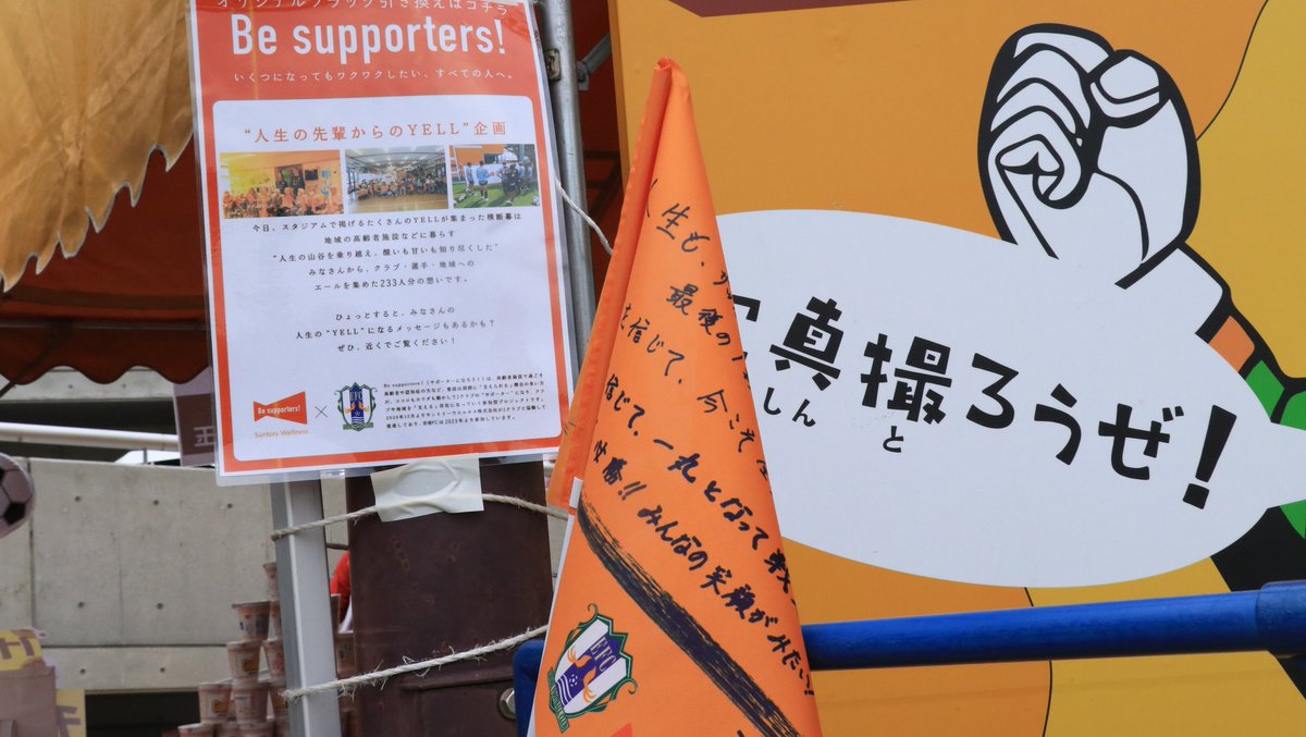 ehime_fc's tweet photo. ／
　#Besupporters！いくつになっても
　ワクワクしたい、すべての人へ📣⚽
　横断幕を掲出しています🏳️
＼

シニアの皆さまのエールが入った横断幕を、イベント広場に掲出しています🙌

選手たちが選んだ熱いエールの入ったオリジナルフラッグのプレゼントも行なっております🎁
詳細はイベントページで✅️
https://t.co/nOizgWiKii

#ehimefc #シャレン
#Beサポ #人生の先輩からのエール