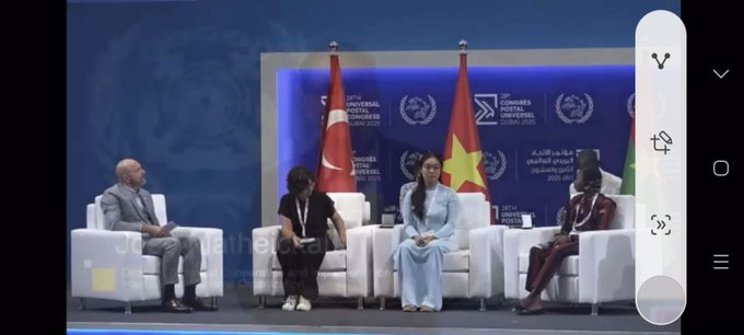 A certificate with the text "54th International Letter-Writing Competition for Young People" and "Reyyan Demiriz" as the first-place winner, featuring the United Nations logo. A gold medal and a black case with the United Nations emblem are beside the certificate. Four people, including Reyyan Demiriz, sit on a stage with Turkish and Vietnamese flags in the background. A large screen displays Reyyan Demiriz’s image with text about her first-place win and the UPU Congress, with an audience seated in front. A group of five people, including Reyyan Demiriz, stands on a stage with a blue backdrop.