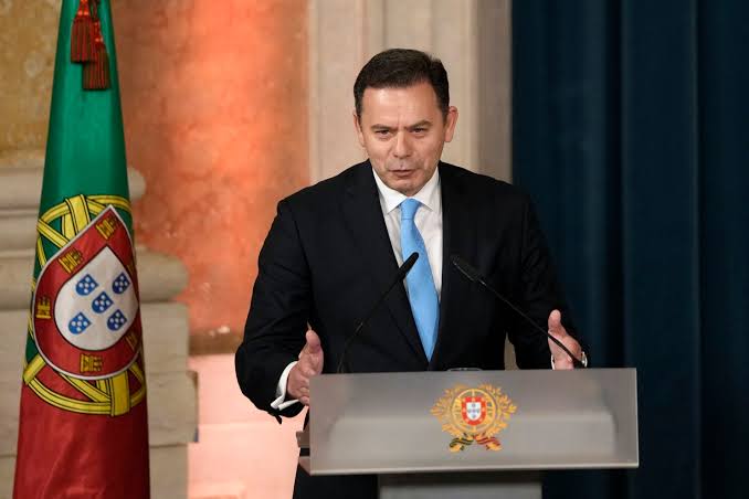 Benjamin Netanyahu standing at a podium with microphones, wearing a dark suit and tie. The Israeli flag is visible in the background. Another image shows a man in a dark suit and blue tie speaking at a podium with the Portuguese flag and emblem.