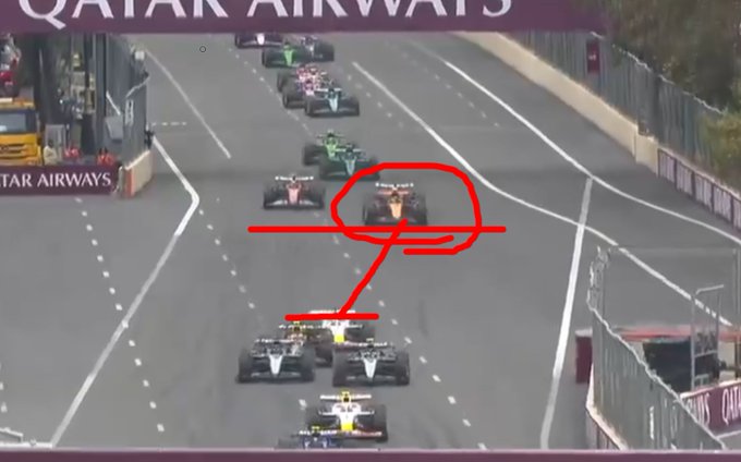 Formula 1 race cars on a track during a restart at the Baku Grand Prix. Multiple cars, including Lando Norris\'s car, are visible on the circuit. The track has clear lane markings and barriers, with a grandstand and "Qatar Airways" signage on the side. A red circle and arrow highlight Lando Norris\'s car, indicating a specific moment.