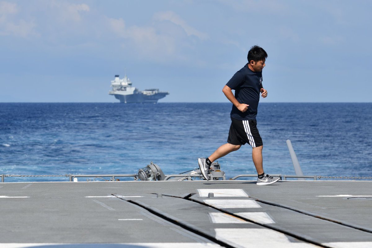 虹とイギリス海軍の空母「プリンス・オブ・ウェールズ」に見守られ