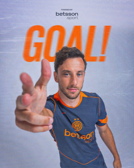 Carlos Augusto wearing a dark blue and orange soccer jersey with "Betsson Sport" text. He is making a peace sign with his right hand and pointing with his left hand. The word "GOAL!" in large orange letters is visible in the background.