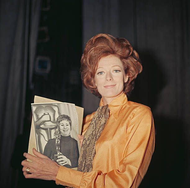 CitizenScreen's tweet image. Maggie Smith pictured holding a photograph of Alice Ghostley accepting the Academy Award for Best Actress on her behalf for her role in THE PRIME OF MISS JEAN BRODIE at the 42nd #Oscars
