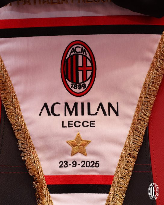 A soccer jersey with the AC Milan logo, featuring a red and black design. The text "AC MILAN" and "LECCE" is embroidered, along with a gold star and the date "23-9-2025." Gold trim borders the jersey section.