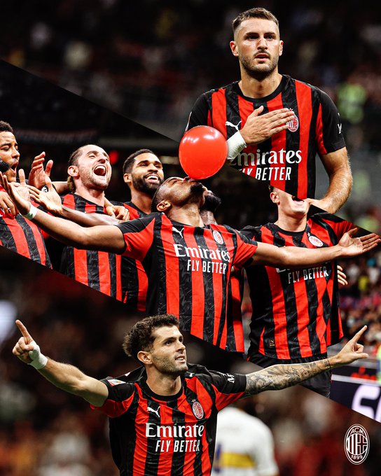 Multiple players wearing red and black striped jerseys with "Emirates Fly Better" text. One player balances a red balloon on his head, another points upward, and others celebrate with raised arms. The jerseys display the AC Milan logo.