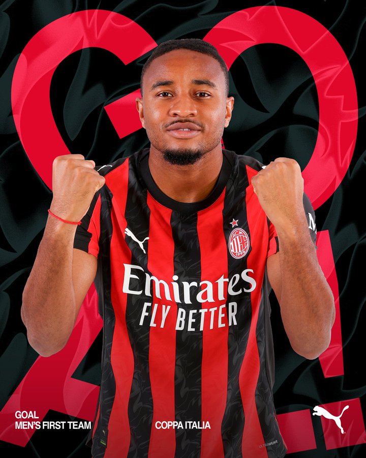 Christopher Nkunku wearing an AC Milan red and black striped jersey with the Emirates "Fly Better" logo. He is posing with fists raised, standing against a background with red and black heart shapes and the text "COPPA ITALIA" and "GOAL MEN'S FIRST TEAM." A Puma logo is visible.