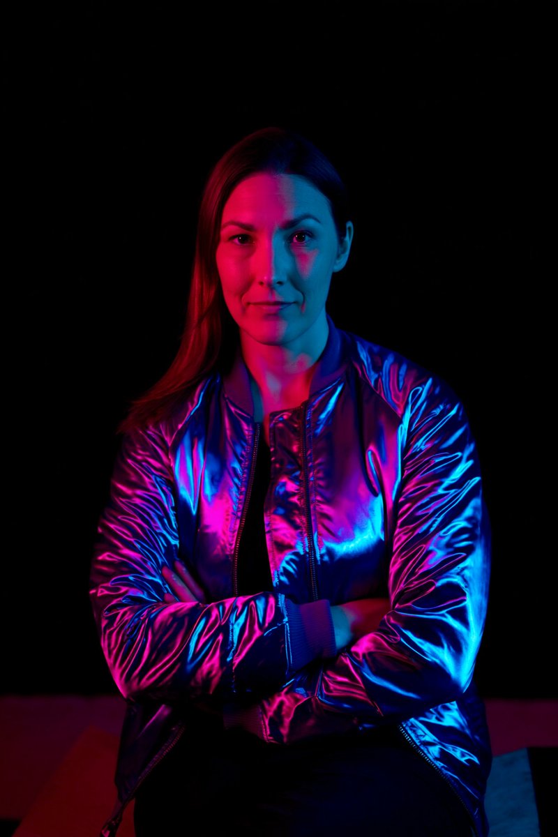 SHOT:  • Composition: Close-up portrait framed from mid-torso, centered, low angle  • Camera Settings: ISO 400, f/2.0, 1/125s  • Film Grain: Soft grain  LENS EFFECTS:  • Optics: Slight diffusion softening edges  • Artifacts: None  • Depth of Field: Shallow, background