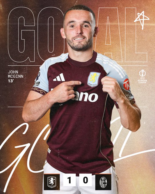 John McGinn wearing an Aston Villa jersey with maroon and light blue colors, pointing at the jersey with both hands. The jersey has the Aston Villa logo and "Banc" text visible. Text overlays include "GOAL" repeated, "John McGinn 13", and a score of 1-0 with Aston Villa and another team's logos.