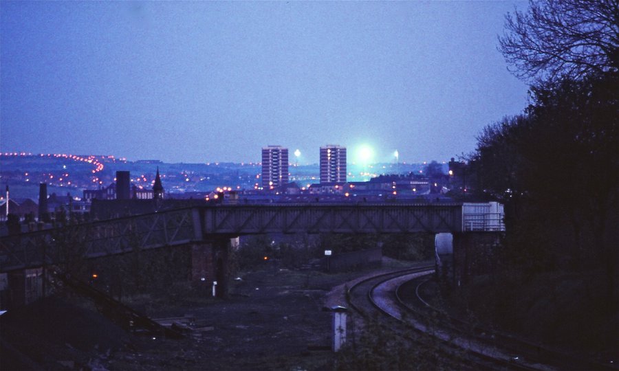 leeds_snippets's tweet image. The bright floodlights of Elland Road shinning behind the tower blocks of council flats in Armley, taken from Cardigan Road sometime in the 1970’s.