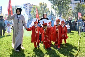 First image displays a large group of adults in formal suits and headscarves standing with young children in school uniforms holding certificates on a stage decorated with red balloons, lanterns, and a banner reading Malatya Muf tusu featuring Arabic script and event name Bed-i Besmele. Second image shows women in headscarves and children holding signs with Arabic text including Amin Alavi and event details, alongside Turkish and Palestinian flags in an outdoor grassy area. Third image captures a woman in abaya holding hands with several boys dressed in red fezzes and robes resembling Ottoman style, walking on grass with Turkish flags and smoke in background. Fourth image depicts a diverse crowd of adults and children, many in headscarves, gathered on grass near apartment buildings with Turkish and Palestinian flags.