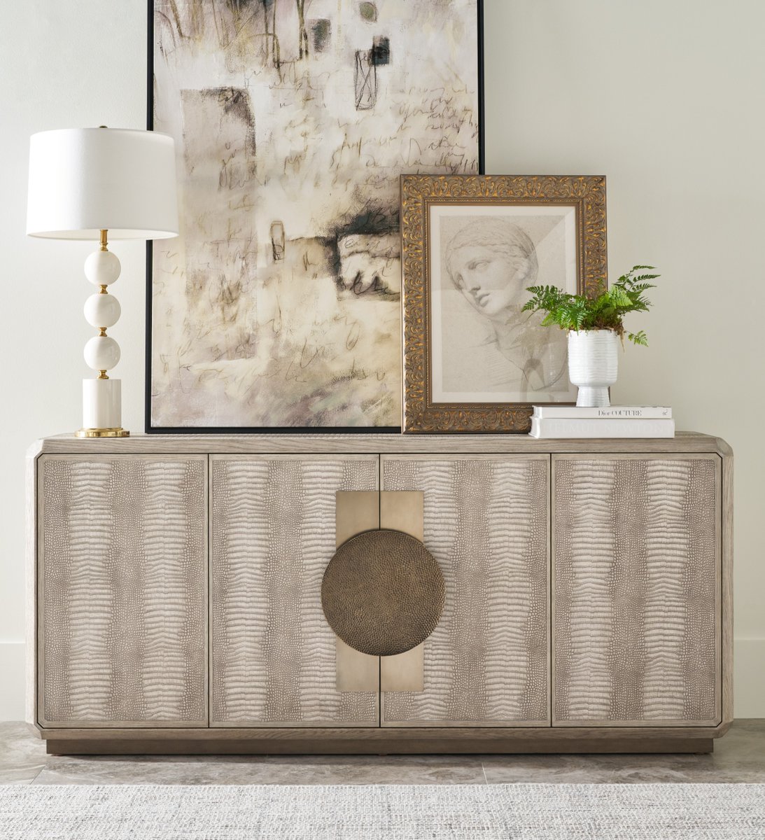The Spencer St. James Credenza blends contemporary flair with exquisite creativity and detail. This four-door piece makes a bold statement with its mix of materials — crafted from oak, wrapped in crocodile-embossed leather, and finished with hammered metal hardware.