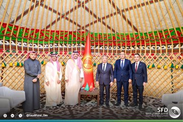 First image shows two men standing side by side in traditional Kyrgyz yurt setting with decorative wall hangings, red Kyrgyz flag with sun emblem, Saudi flag, and green flag; one man in white thobe and red checkered headscarf holds green folder with Saudi Fund for Development logo, the other in dark suit holds red folder, both smiling formally. Second image depicts the same two men seated facing each other across a low table with water bottles and flags including Saudi, Kyrgyz, and another green flag, in similar yurt interior with embroidered decorations and chairs. Third image features six men standing in group pose in the yurt with ornate green and red wall panels, central tall red Kyrgyz flag, various flags on table, men in suits and traditional attire including thobes, all positioned formally around furniture.