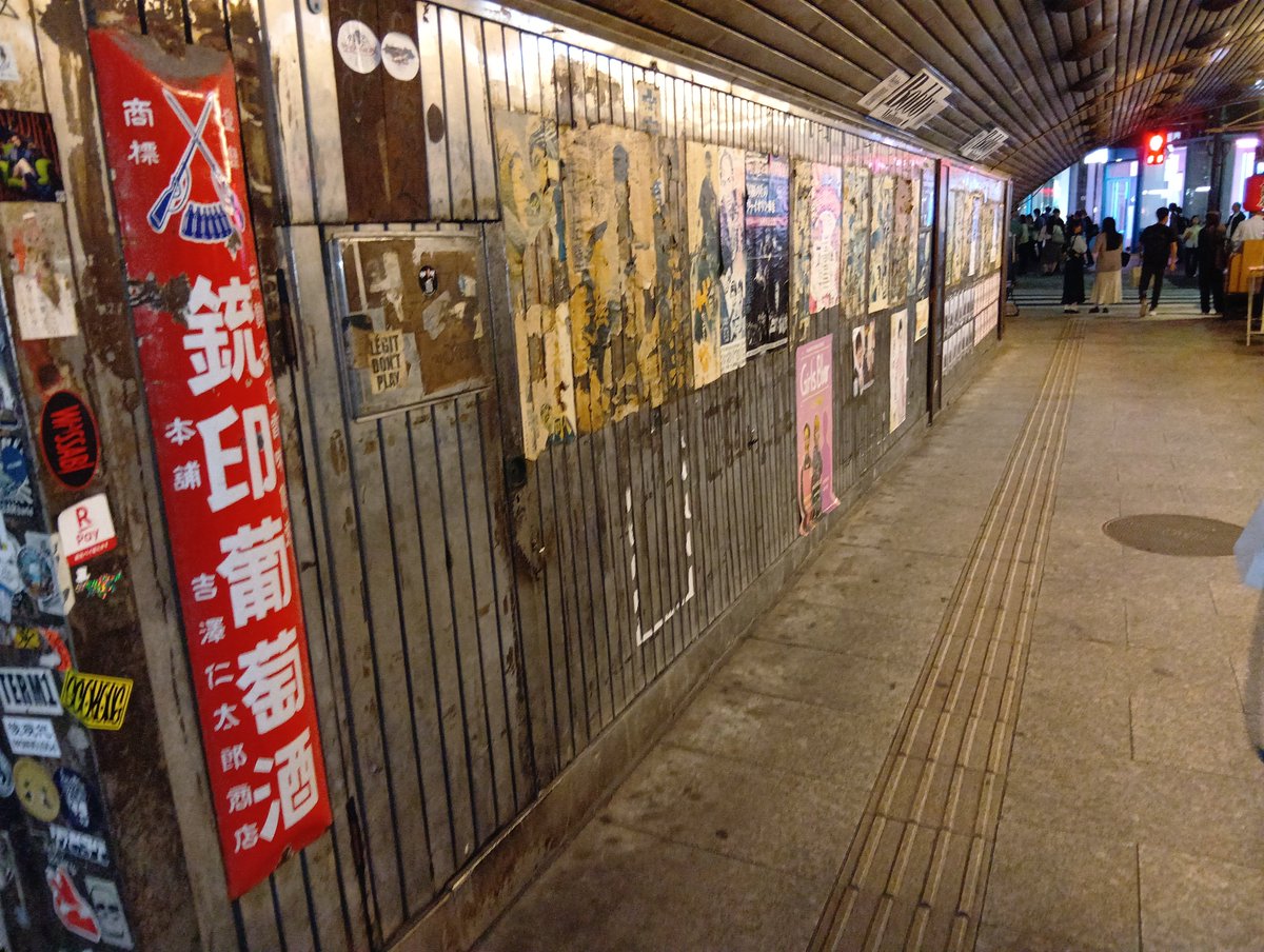 有楽町ガード下飲み屋の向かいの壁に貼られる昭和の映画ポスター（剥がれ退色見づらい）