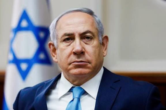 First image shows Benjamin Netanyahu, an elderly man with white hair, wearing a dark suit, white shirt, and blue tie, standing in front of two Israeli flags in what appears to be an official indoor setting. Second image depicts Vladimir Putin, a man with short white hair, dressed in a dark suit, white shirt, and tie, with a neutral expression against a plain background.