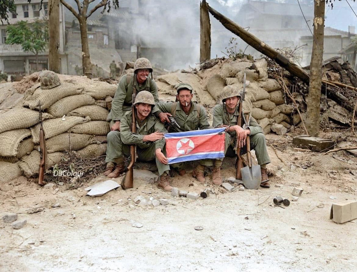 Sgt Russelll Evans, S/Sgt Jack Fichter, and Pfc Wendel Champeon, with Pharmacists Mate 3rd class John D. Epperson show off a captured North Korean flag taken in the fighting for Seoul in South Korea.