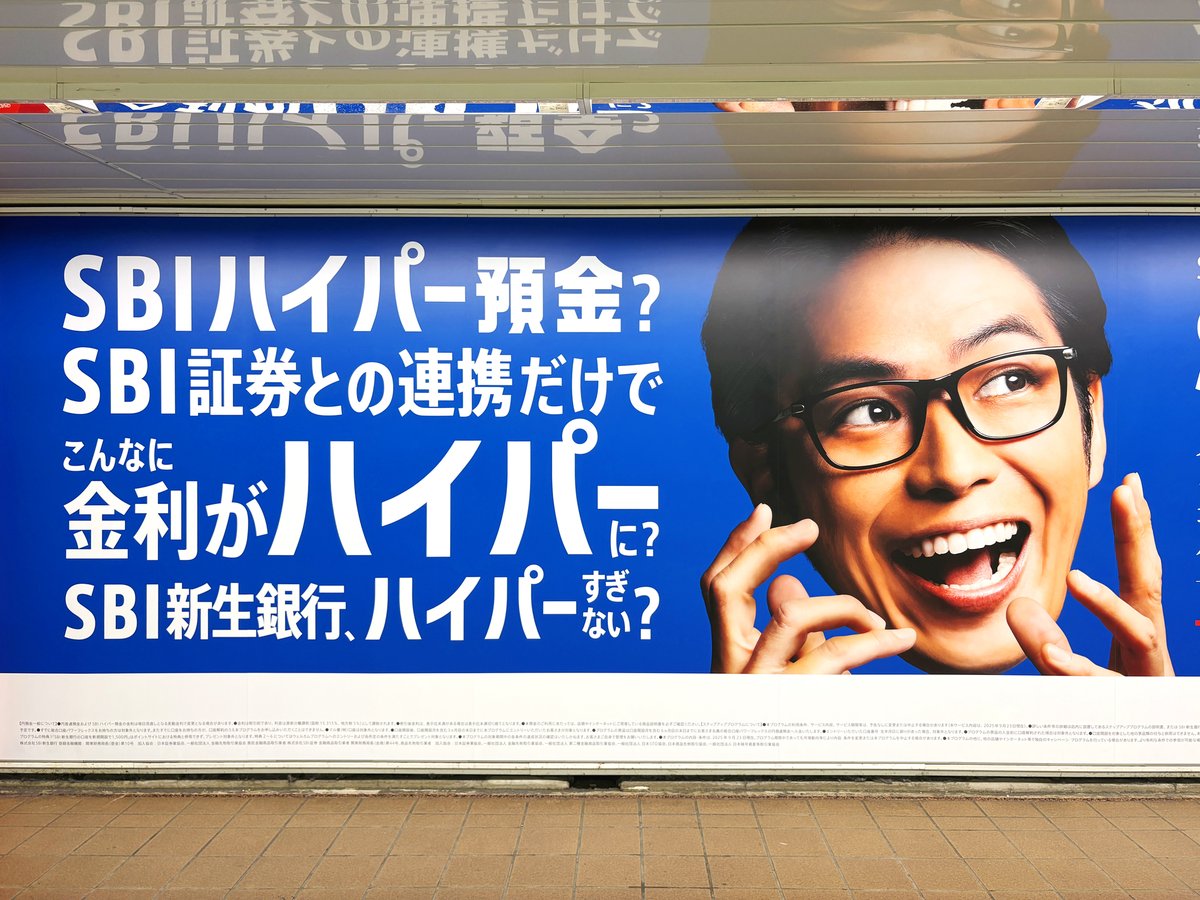 新宿メトロプロムナードに「SBIハイパー預金」の広告が展開中。特大シートと柱サイネージを使って、お得な情報を大きな文字＆笑顔のアップでアピールしています😀  乗り換えなどでこの通路を使う人にとっては、長い時間視界に入って印象付けされそうですね👀