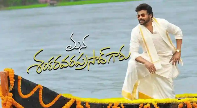 Chiranjeevi stands on a wooden boat decorated with yellow marigold garlands near a body of water with green backdrop. He wears a white dhoti and kurta with a yellow shawl draped over one shoulder and a watch on his wrist posing confidently with hands on hips. Yellow Telugu text overlay reads Manasu Sogusuga and Sokaravarsam across the image.