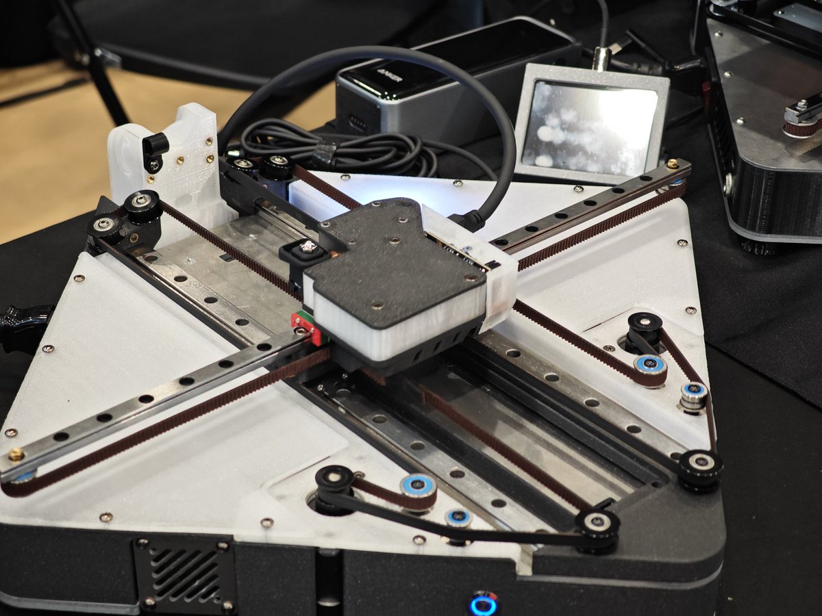 Positron3d's tweet photo. This weekend, we revealed The Proton.

The Alpha has us at a 300x260x260 volume, and we are expecting sub $1,000 price point, even sub $700 if possible.

But, we are likely a year out from a Beta release. We have a LOT of things to work on.

But notably;
1. Mostly 3D Printed Design (can be printed on a MK3, Beta will aim for a Prusa Mini/Positron)
2. Full Nozzle Probe thanks to Amplify and Ella Fox.
3. The Quark Board, a Power Continuity board designed by our team member Koosh, and allows you to run ANY 24V printer off a USB C power Bank. Your runtime is only limited to the bank, but we had a small one at Printopia and could get 45 minutes when printing on the Proton. Positron, about an hour and a half, and something like a Cocoa Press could run for multiple hours.
4. Still Foldable - can store away easy when a larger printer is not needed.
5. All Metal Heat break to allow temps above 290⁰C
6. Direct Drive Extruder, we didn't have Gluon to show off, but with the new tool head, we plan to have direct drive baked in.
7. Electronics Flexibility - we designed the Proton to support BTT boards, a Einsy Rambo, and a Positron Board, more likely will come.
8. Internal (enclosed) PSU - easy and safe to install, whole printer is sub 400 watts.
9. Dual Layer PCB heater - quickly heat up with both, only use one when on battery power.

Things we hope to change for Beta, but no promises;
1. Simplify CNC parts - currently, they are a bit over engineered, we will likely be looking at bent sheet steel to reduce cost.
2. Improved Quark Board - we want this to be able to not only power the printer, but safely use PD to power your phone or laptop so you can leave one more charger at home.
3. Get Gluon working

Let's be real - we first got this printing 2 days before the event 😂 massive shout-out to the team for sticking the landing.