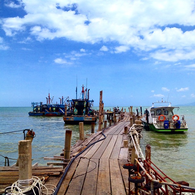 Wooden pier stretching into turquoise waters, where fishing boats and the open sea meet the horizon 🌊⚓️ Sometimes the simplest views are the most calming. #OceanVibes #SeaEscape #TravelMoments