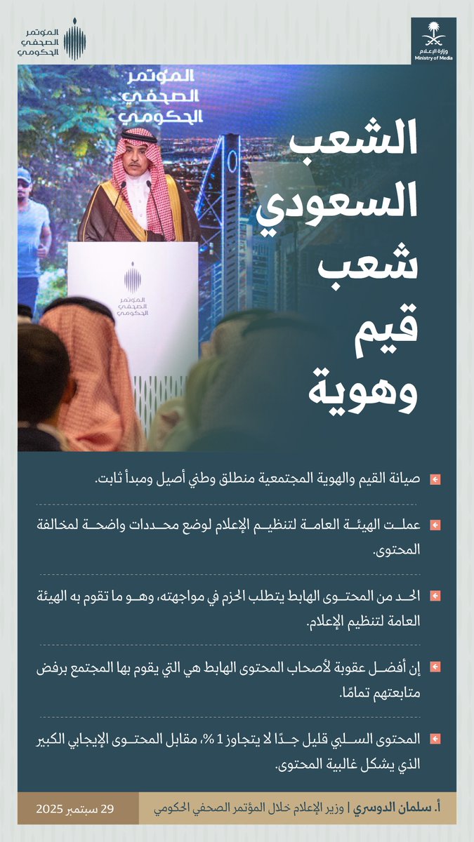 A person in academic regalia speaking at a podium with a microphone. Another person in traditional attire stands nearby. A backdrop displays the logo of the Saudi government and text in Arabic. Additional text in Arabic is visible on the image.