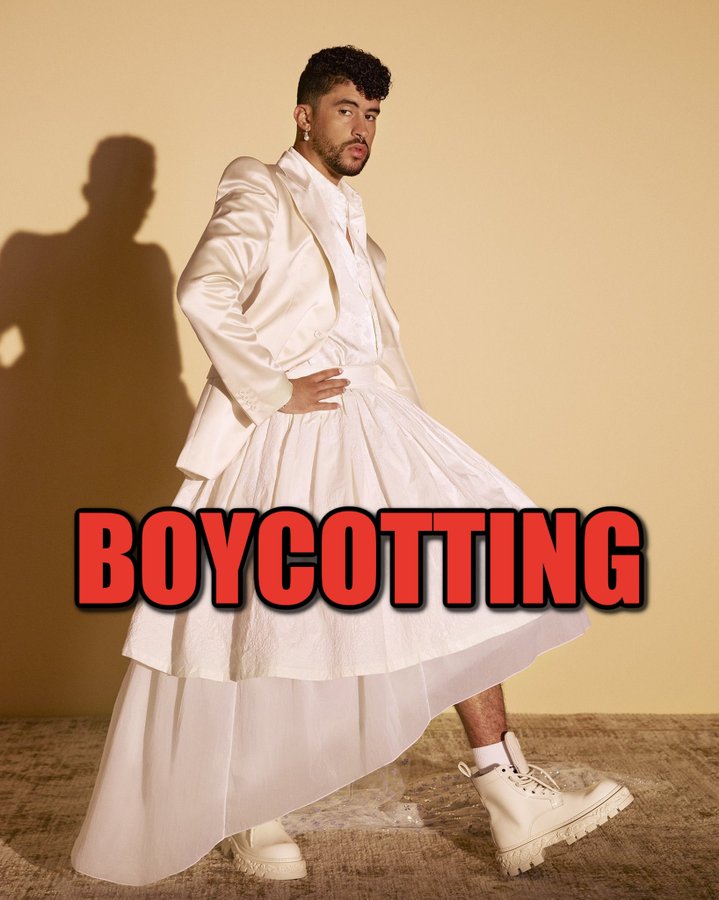 Bad Bunny wearing a white suit with a long, flowing skirt and white boots, standing with one hand on his hip. The background is a plain yellow, and a shadow of his figure is visible. Red text overlay reads "BOYCOTTING".
