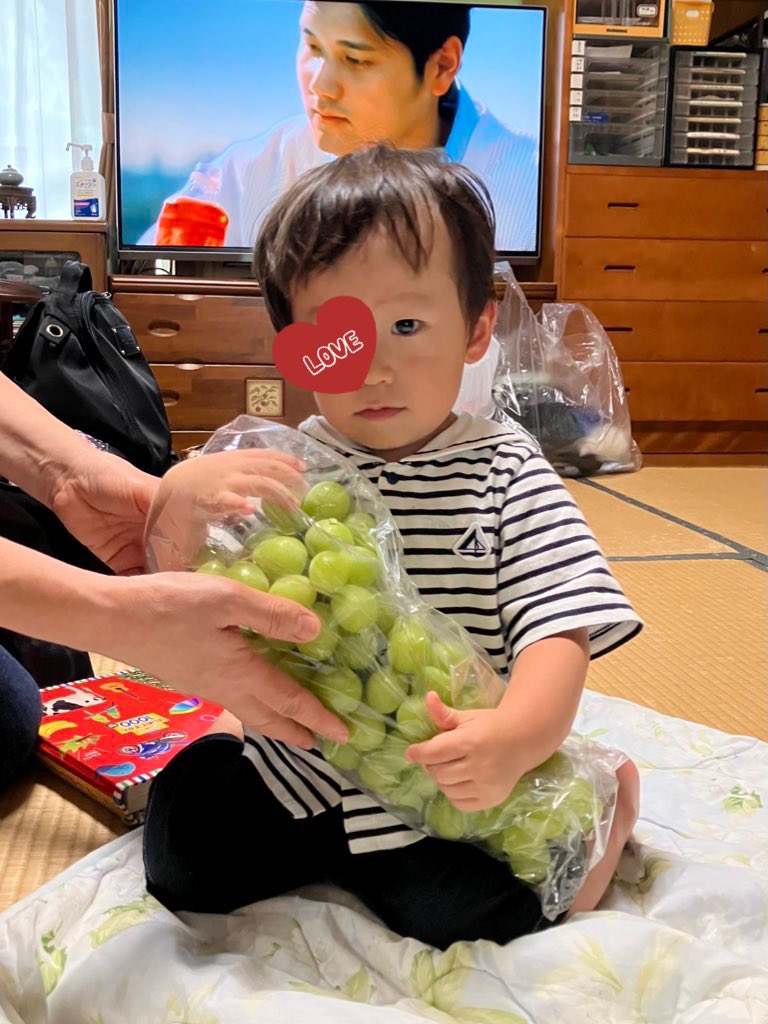 曾ばぁばがくれたシャインマスカットがでかすぎる。長男くんはヒシッと抱きかかえてコレ俺の！とアピール中です。