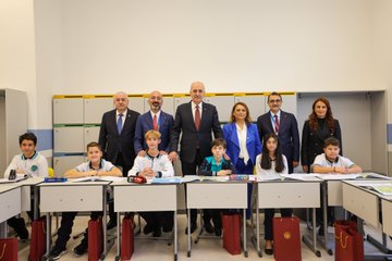 Numan Kurtulmuş and László Kövér standing at a podium with microphones, flanked by Turkish and Hungarian flags. A group of people, including children, cutting a ribbon in front of a Maarif Vakfı logo. Students and adults posing in a classroom with desks and educational materials. An audience seated in chairs at an event with a banner reading "Török-Magyar Innovációs Év 2019".