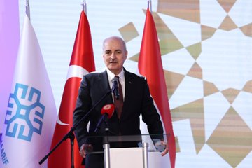 Mahmut Özdil speaking at a podium with Turkish and Hungarian flags, microphones, and a backdrop with geometric patterns. A group including Numan Kurtulmuş, Laszlo Köver, Fatih Dönmez, and Gülşen Karanis standing together cutting a red ribbon at a ceremony. Mahmut Özdil addressing an audience at a podium with flags and a backdrop featuring text "TÜRKİYE 2023". Mahmut Özdil and others standing with students in a classroom setting with desks and educational materials.
