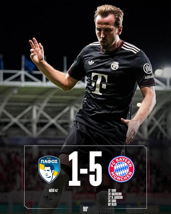 Thomas Müller wearing a black FC Bayern jersey with white and red accents, raising his right hand in a gesture. The jersey displays the FC Bayern logo and Adidas branding. A scoreboard overlay shows a 1-5 score between PAOK and FC Bayern Munich, with player names and times listed below.