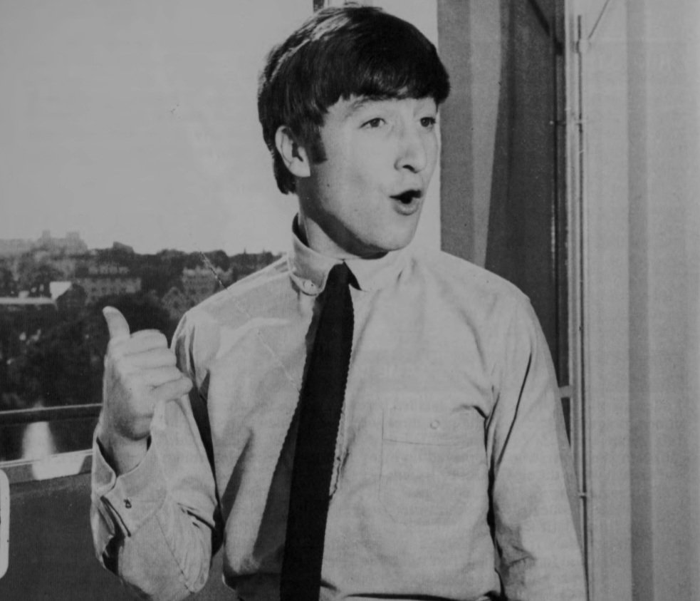 john lennon at brian epstein's office. according to the beatles monthly book, john was shocked by a fan holding a sign with his name on it (december, 1963)