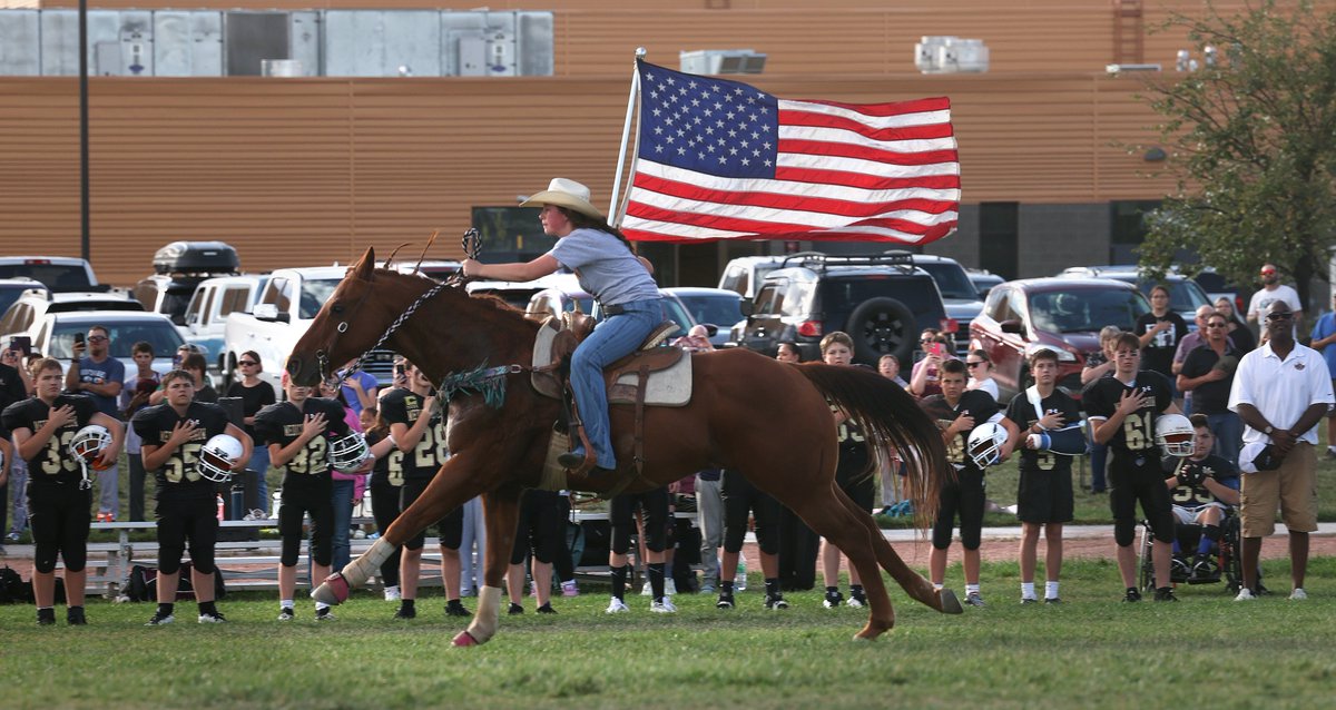 Seventh-grader Braelin Davis and her horse Dillon run past the football team during the National Anthem at Medicine Crow Middle School in Billings, Montana.
