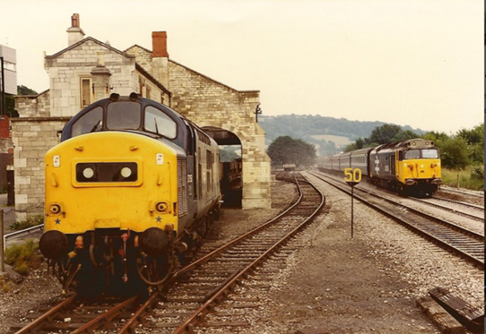 Morning. Off to Stroud today. Here it is on a Sunday evening in 1984. While 37159 shunts ballast wagons through the old goods shed at Stroud, 50038 FORMIDABLE arrives with a service from Paddington. 📷 Alan. Click the link to see his Flickr pages.  
flickr.com/photos/acd40/4…