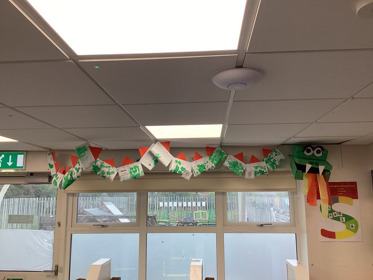 SpringfieldPri1's tweet image. The big dragon we made in Woodpeckers from painted boxes and mark making has found his way onto our ceiling. He is going to be joined by shields we made and is decorated with the adjectives we used to describe him in English