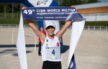 Two fencers in white uniforms and masks lunging on a purple mat, holding foils. Swimmers in red and blue swimsuits poised on starting blocks above a pool. An athlete in a white tank top and number 4 bib holding a banner reading "49th CISM World Military Pentathlon Championships POLAND - DRZONKOW / ZIELONA GORA 2023." Athletes on a podium holding flags of Egypt, Turkey, and Poland, displaying medals.