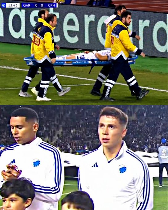 Personal médico con uniformes amarillos y negros cargando a Rodrigo Huescas en una camilla en una cancha de fútbol. Rodrigo Huescas está acostado en la camilla, vistiendo una camiseta de fútbol blanca con detalles azules. Jugadores con camisetas blancas similares con detalles azules se paran en el campo, luciendo preocupados. Un marcador y asientos de estadio son visibles en el fondo.