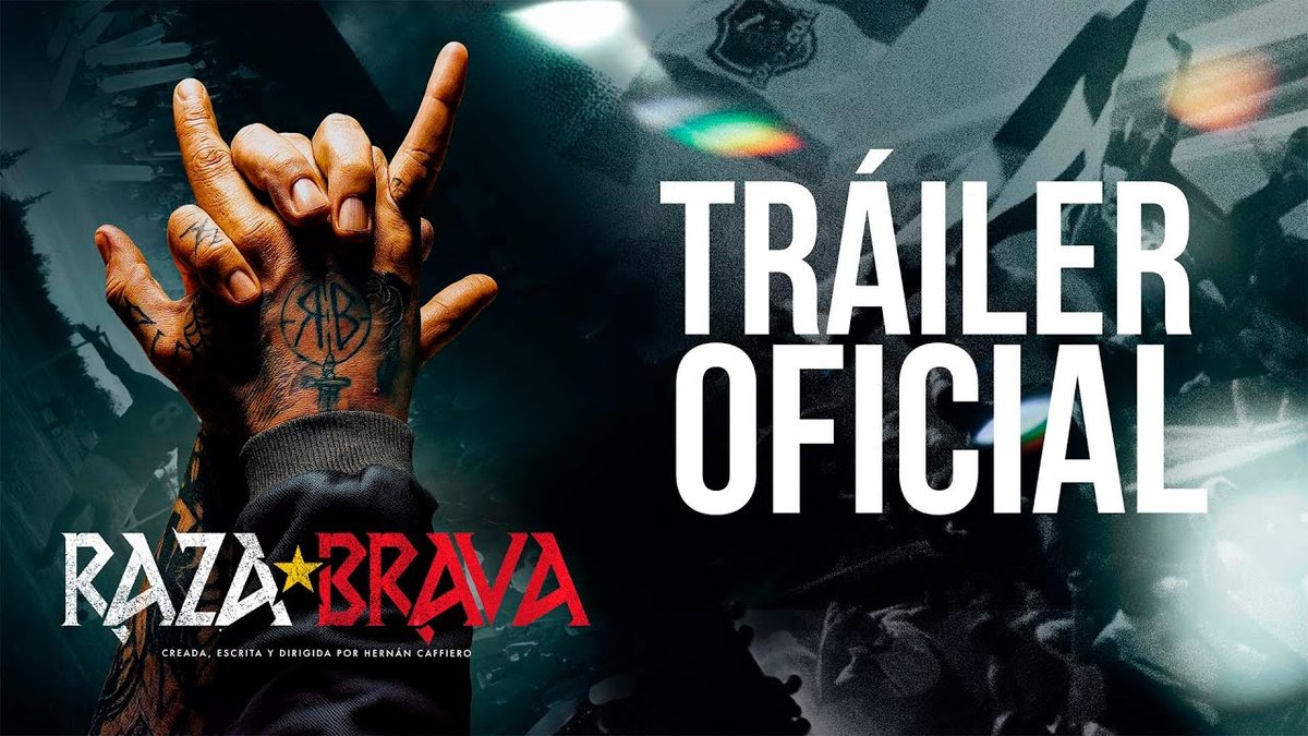 A hand with tattoos making a fist and raising index and pinky fingers in a rock gesture, wearing a dark jacket sleeve. The text "TRÁILER OFICIAL" is prominently displayed in white capital letters. The logo "RAZA★BRAVA" with red and black text is visible, along with smaller text below it.