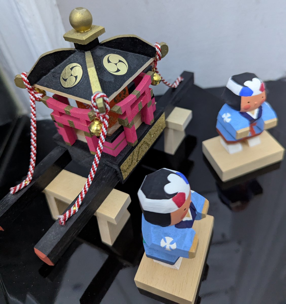 October's decoration shows two festival goers with a mikoshi, a palanquin with a deity enshrined inside. The mikoshi is used to transport the deity. Festivals in October that involve a mikoshi include Nada no Kenka in Himeji, Hyōgo, and Ueno Tenjin Festival in Iga, Mie.