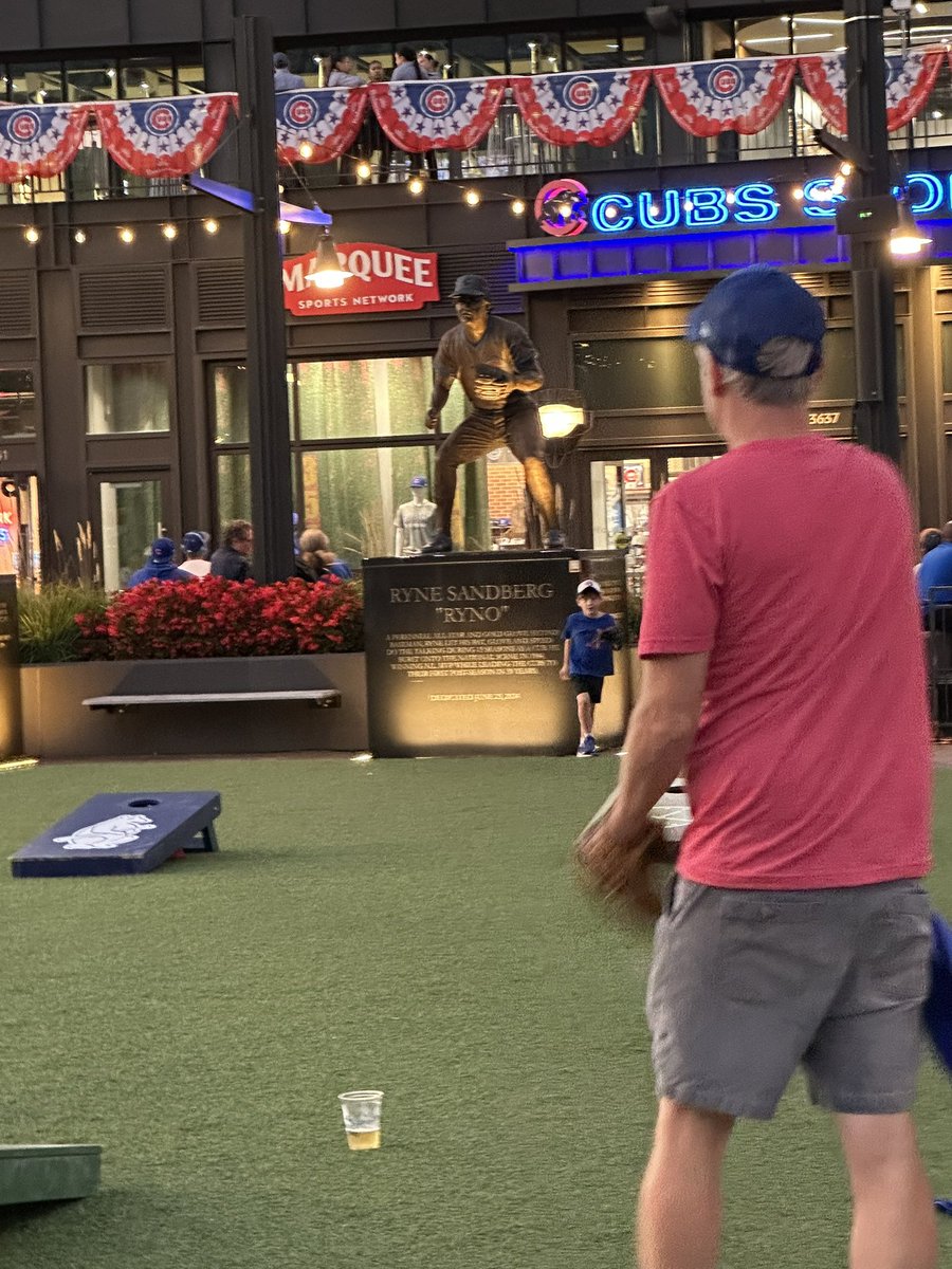 A father and son play catch in front of the Ryno statue as the Cubs try to finish off the Padres in the playoffs.